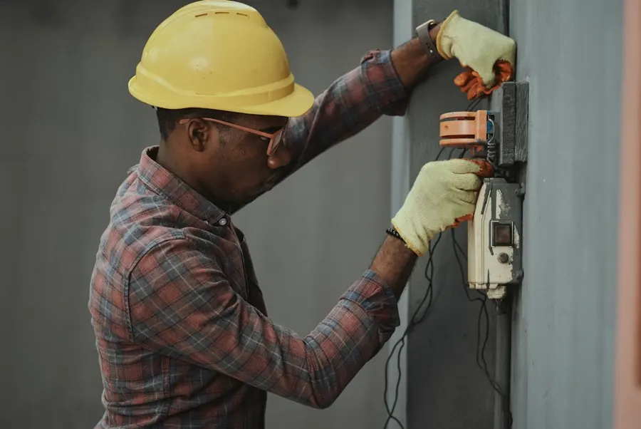 Électricien avec casque de chantier intervenant sur un tableau électrique